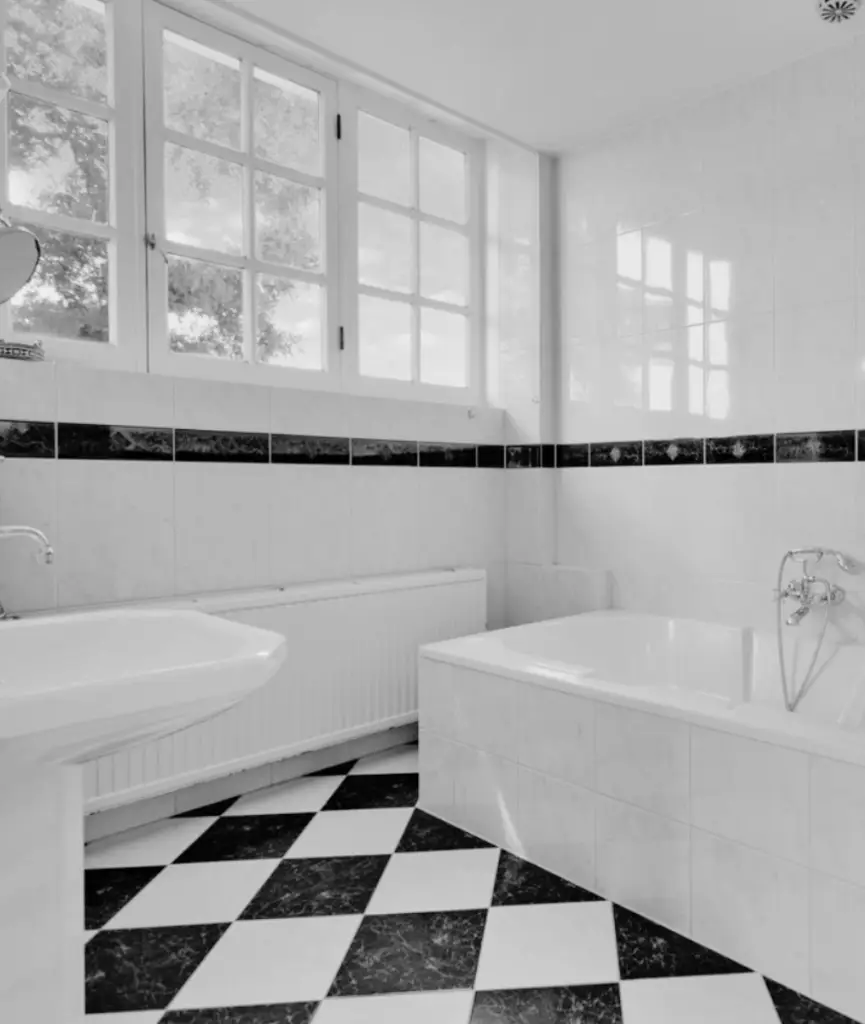 Oude badkamer met zwart-wit tegelvloer en ligbad – Villa aan de Leede