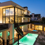 Avondopname van villa Noordwijk met verlicht zwembad en poolhouse