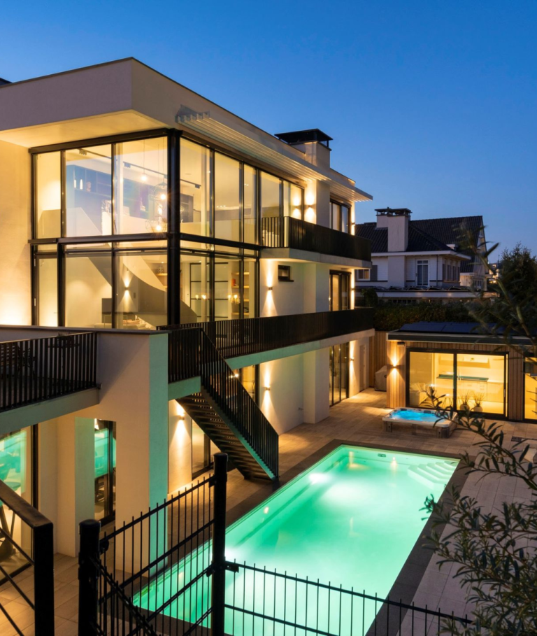 Avondopname van villa Noordwijk met verlicht zwembad en poolhouse