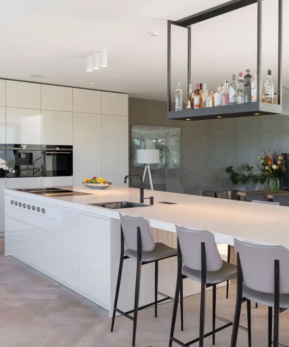 Luxe keuken met wit kookeiland en flessenrek in villa Noordwijk