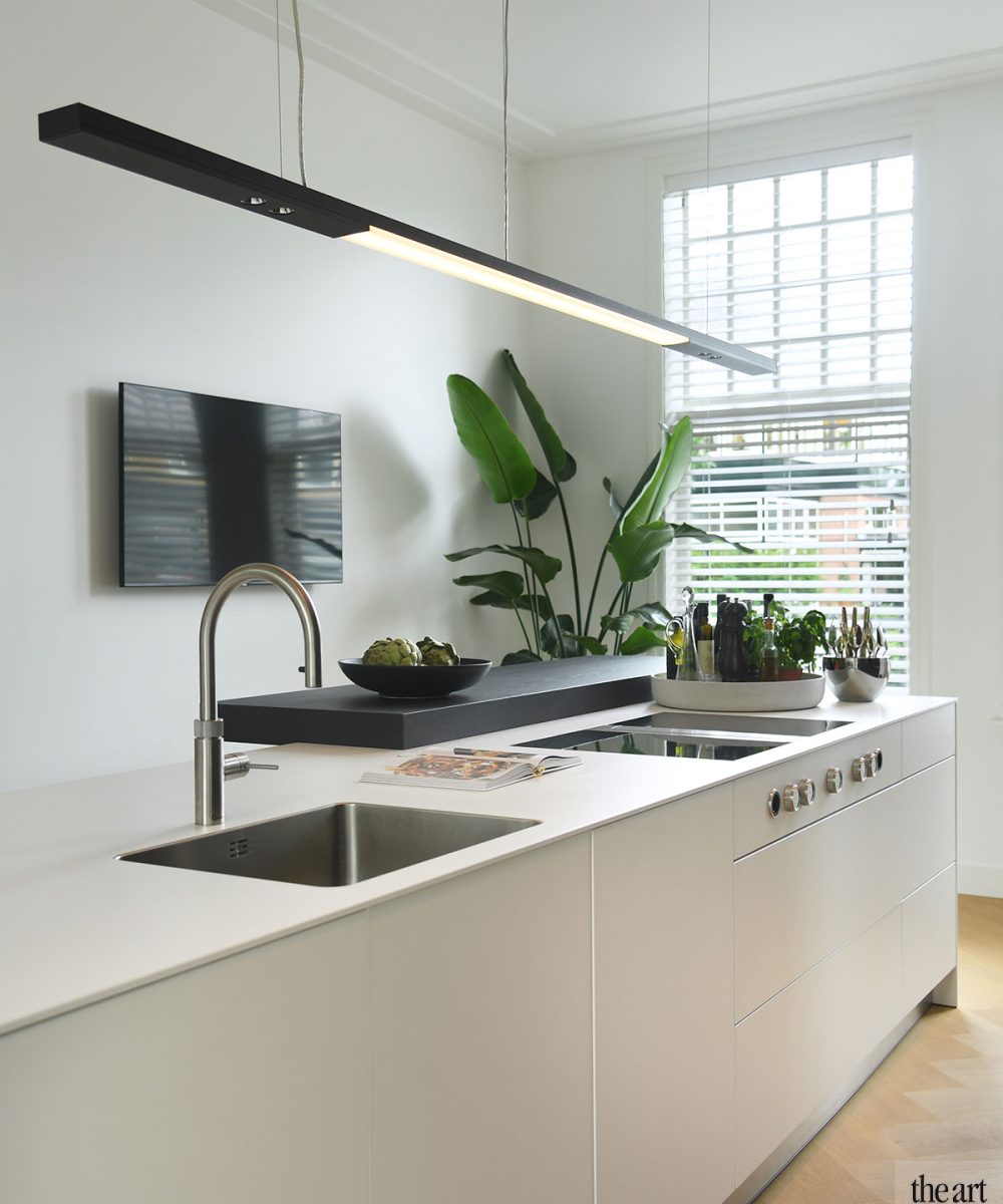 Wit kookeiland met kraan en hanglamp in de keuken