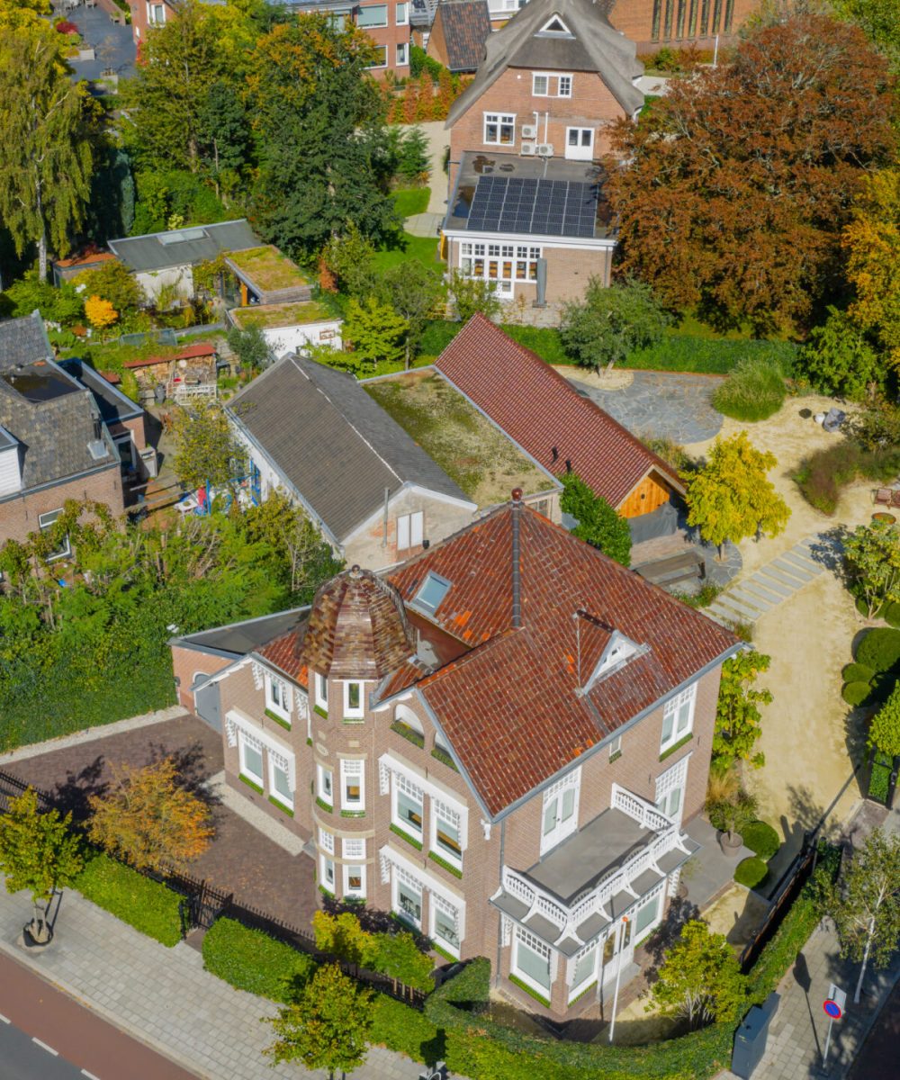 Luchtfoto van Huize INA in Oegstgeest, een landhuis uit 1912 met torentje, met de tuin en het tuinhuis met garage