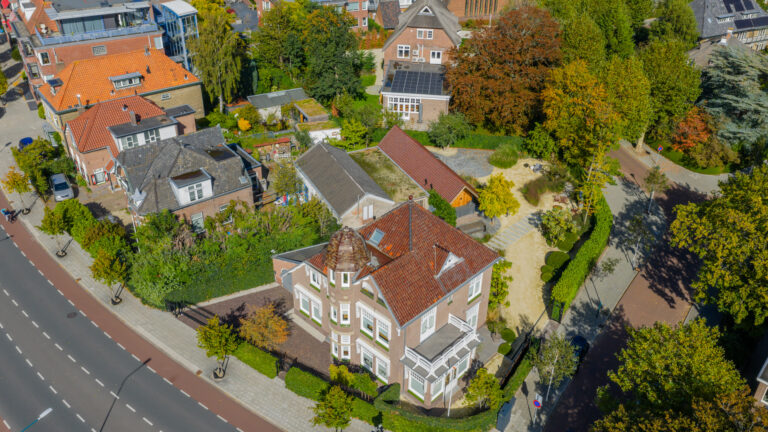 Luchtfoto van Huize INA in Oegstgeest, een landhuis uit 1912 met torentje, met de tuin en het tuinhuis met garage
