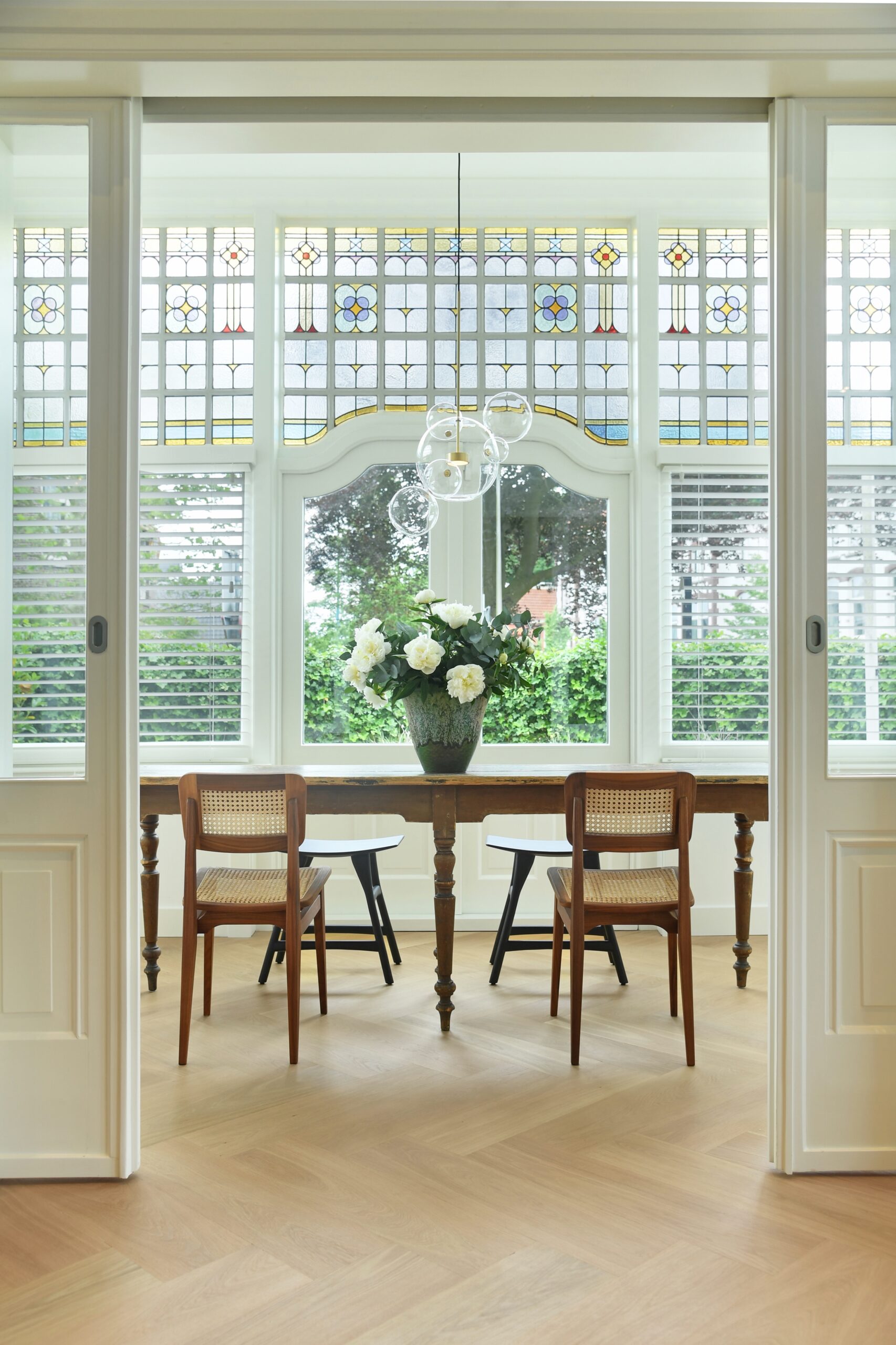 Serre met originele glas-in-loodramen en openslaande deuren, gezien vanuit de woonkamer