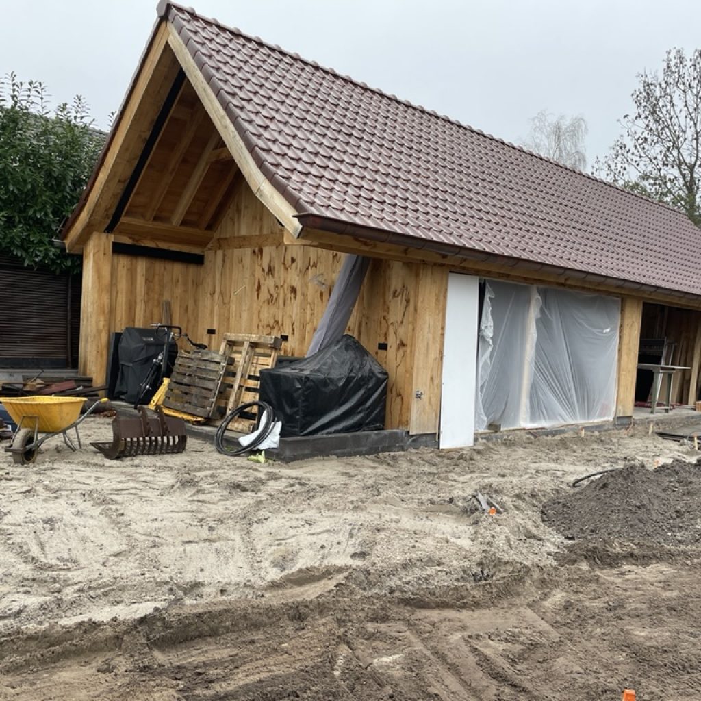 Het houten bijgebouw met garage en buitenkeuken in aanbouw, tuin van Huize INA in Oegstgeest