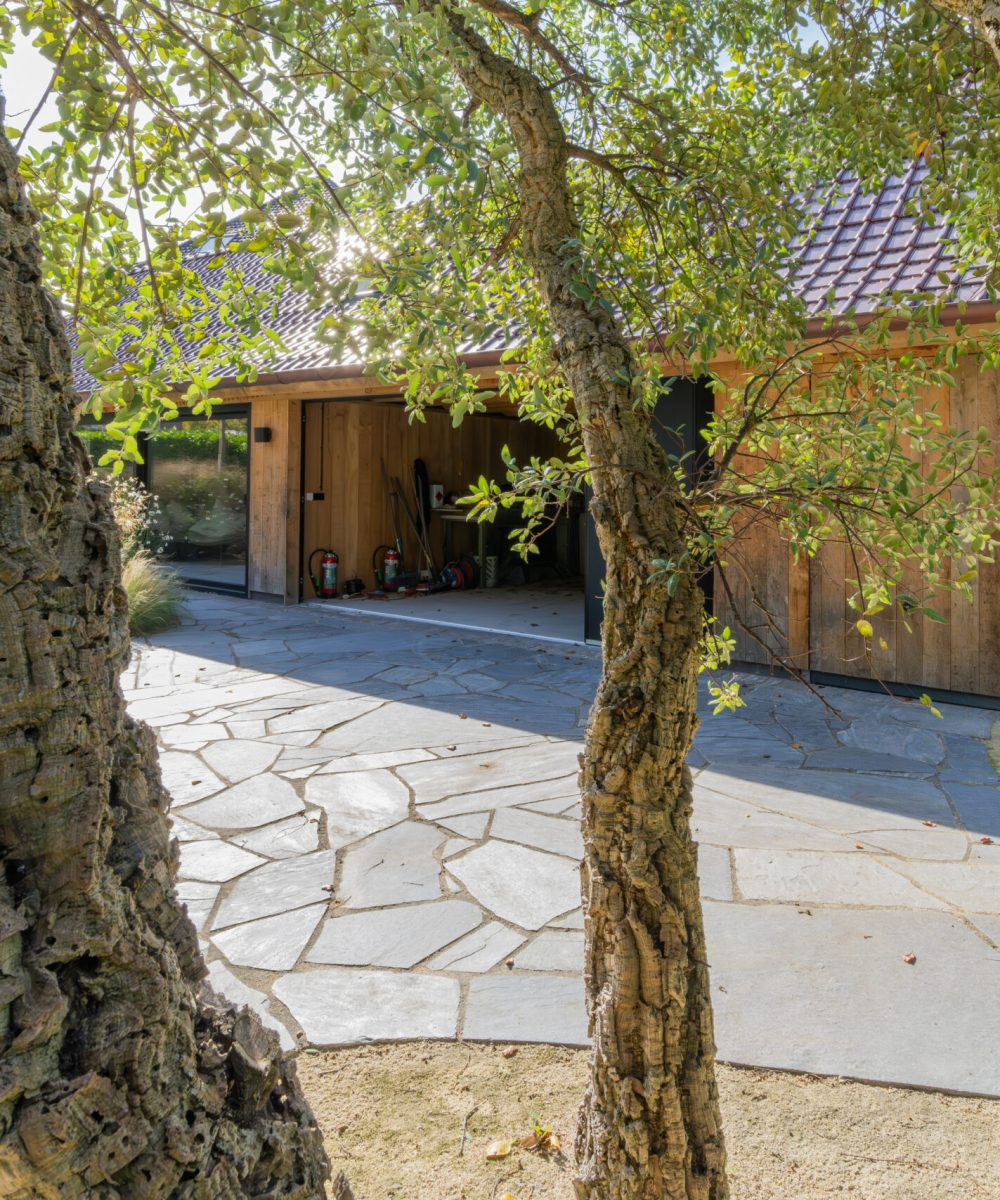 Keerpunt van natuursteen bij het houten bijgebouw, gezien tussen de stammen door