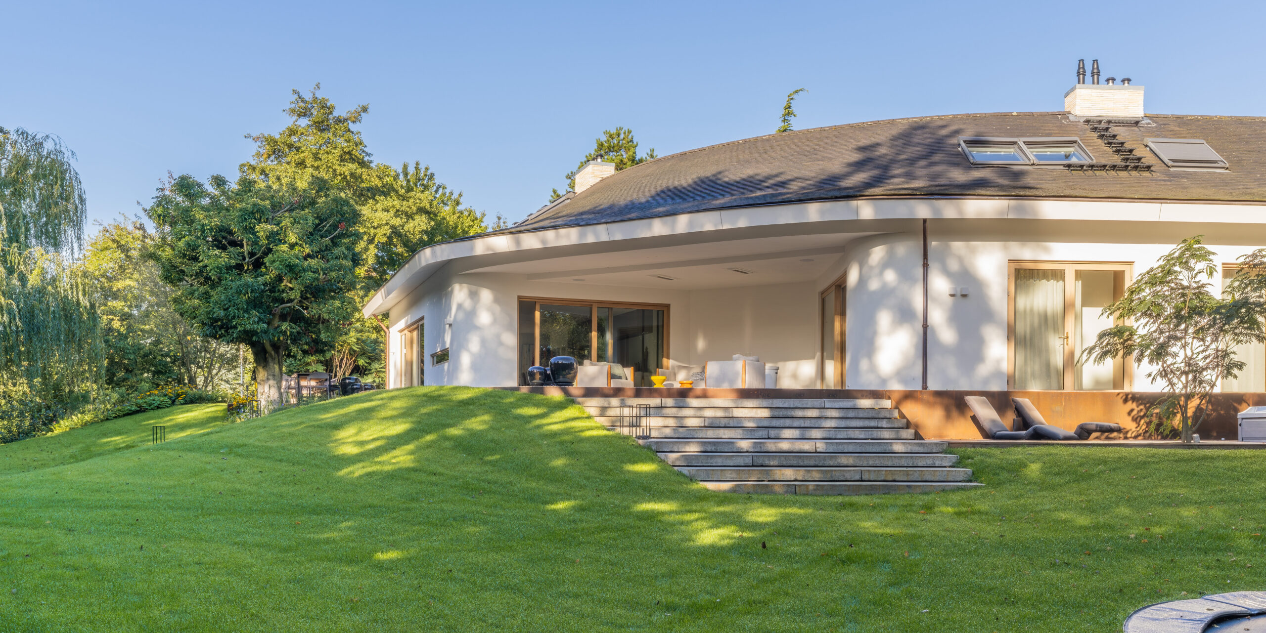 Achtertuin van Villa Boechorst in Noordwijk na de aanleg, met een open gazon, brede traptreden en een overdekt terras