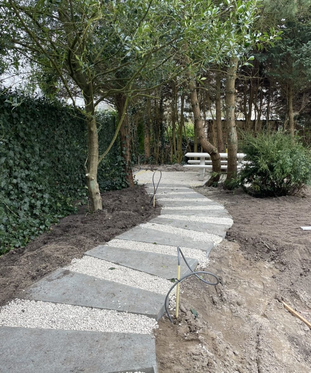 Pad van grote stapstenen onder de bomen in de tuin van Villa Boechorst in Noordwijk. Tuinontwerp KamerlingvanderBurgh.