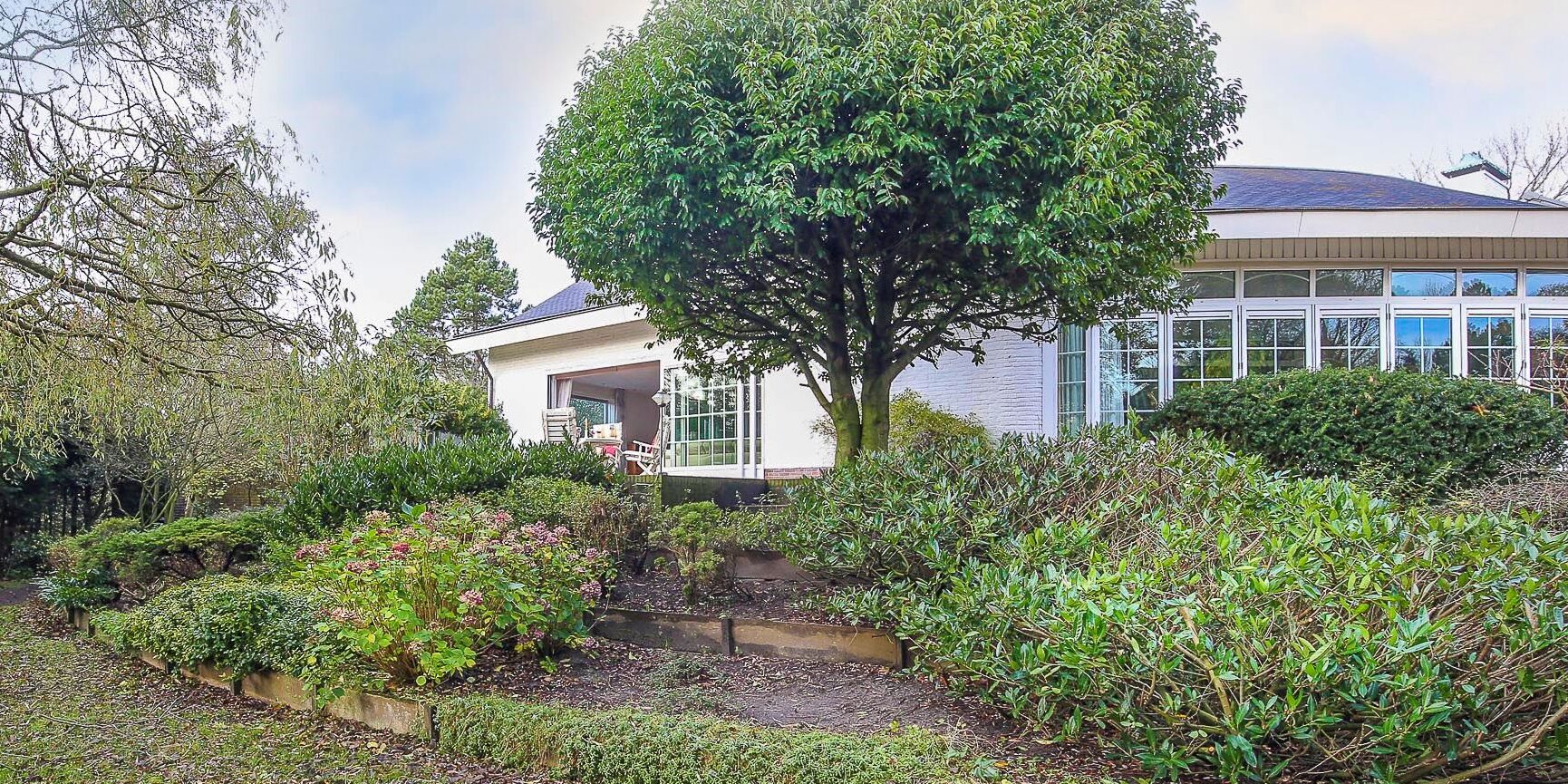 Achtertuin van Villa Boechorst in Noordwijk voor de aanleg, met dichte borders en een vouwpui met kleine ramen