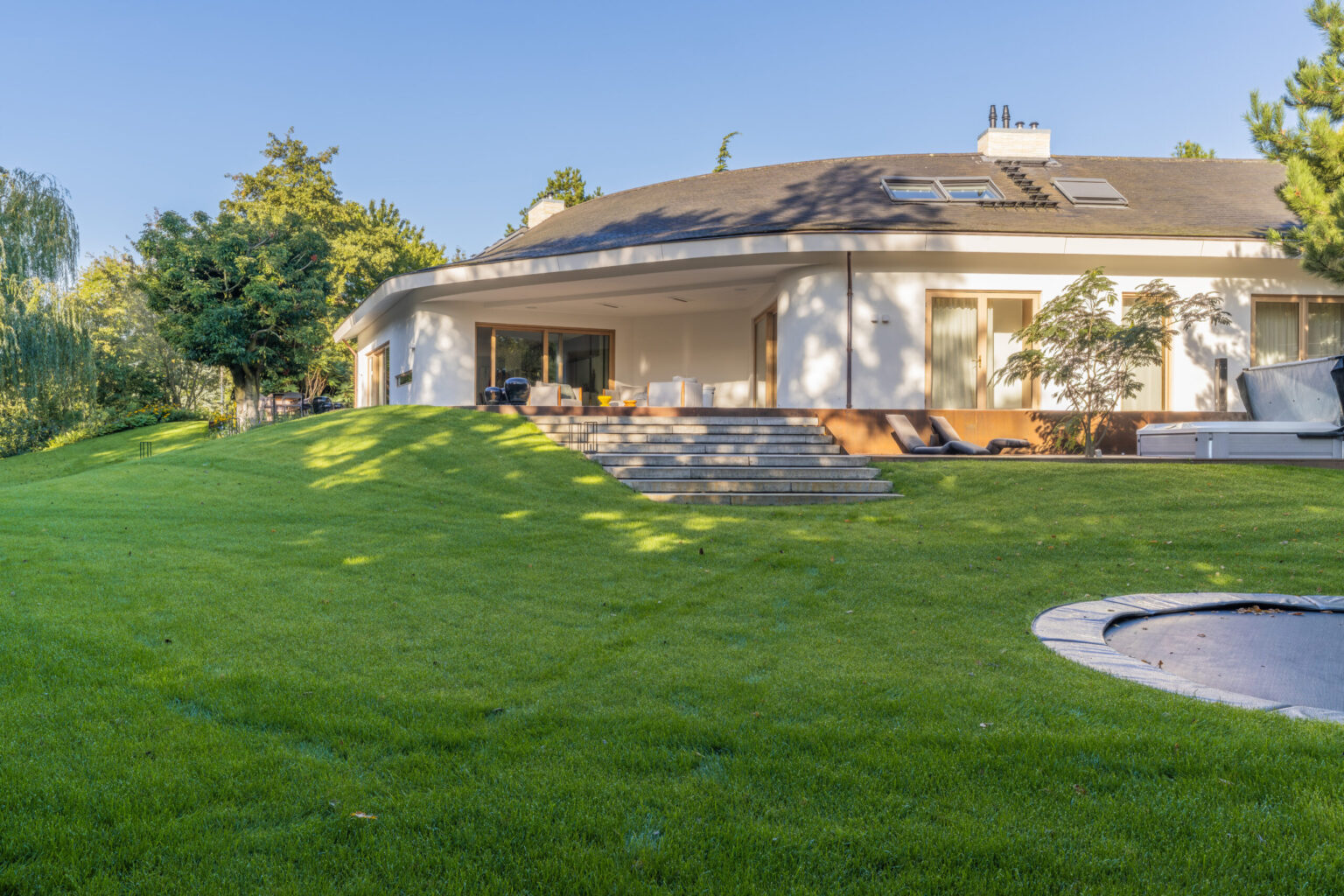 Achtergevel van Villa Boechorst in Noordwijk na de verbouwing, met een overdekt terras op de plek van de vouwpui en brede traptreden naar het gazon