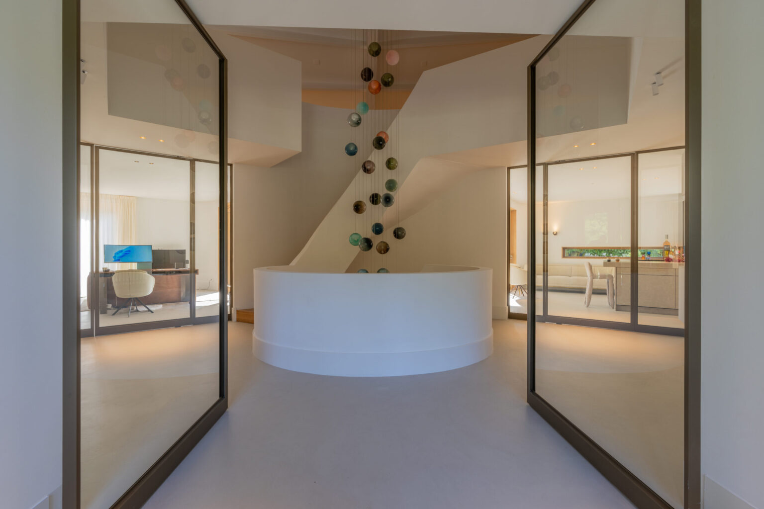 Hal van Villa Boechorst in Noordwijk na de verbouwing, met een sculpturale trap, ronde zitbank en glazen wanden
