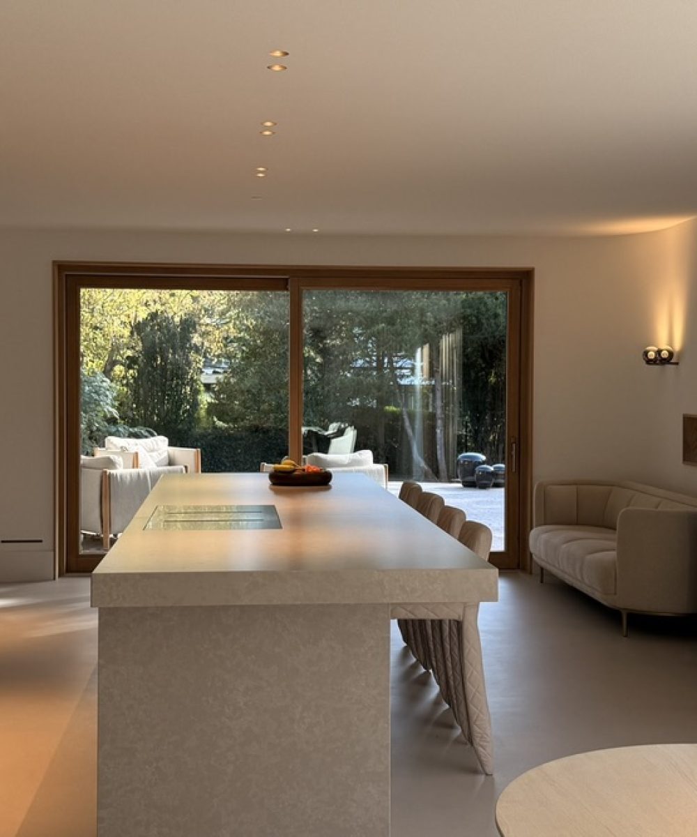 Lange woonkeuken in Villa Boechorst in Noordwijk met een kookeiland en zicht op de tuin