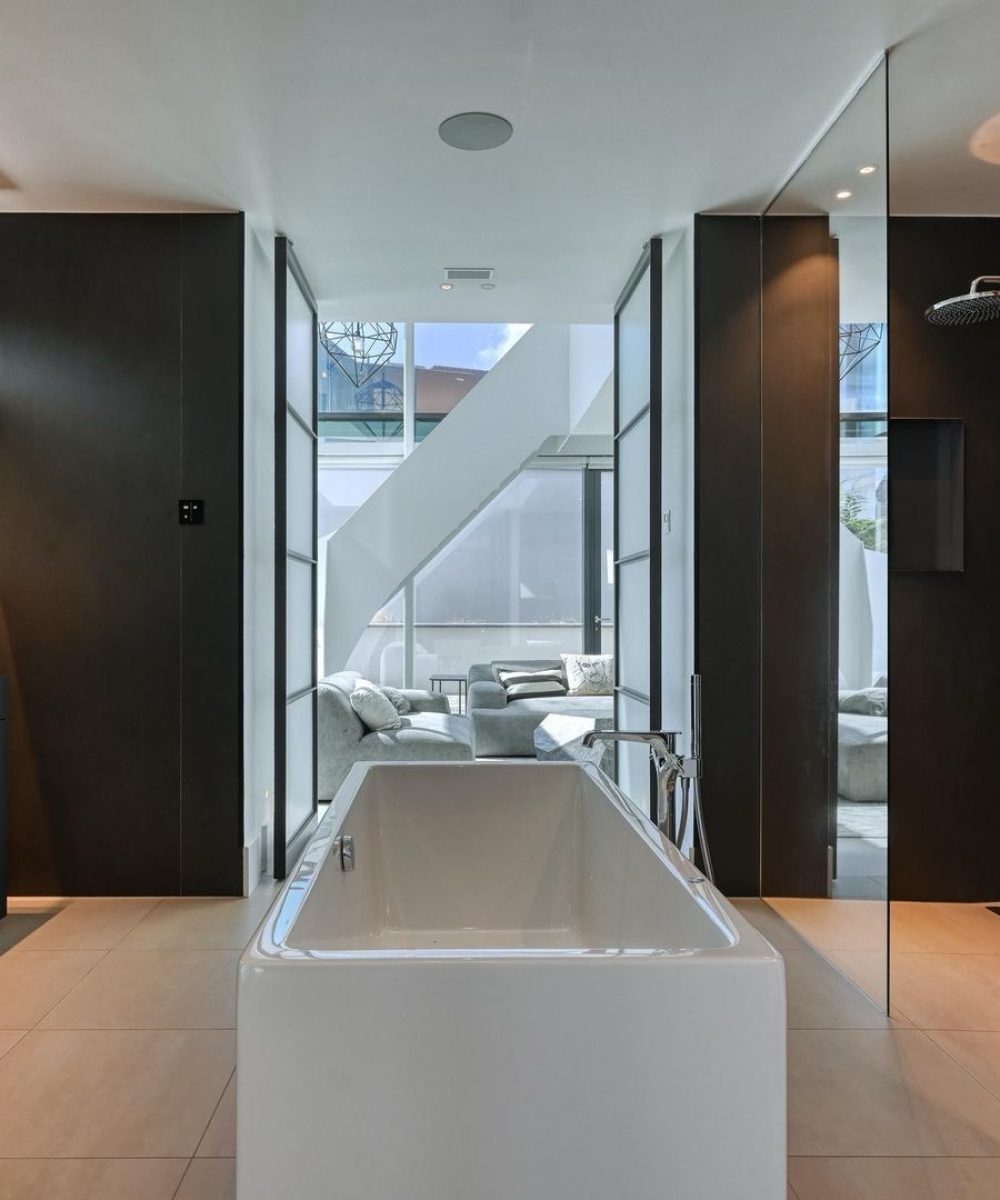 Badkamer met vrijstaand bad en donker maatwerk in Villa Zuidduinen in Noordwijk. Ontwerp KamerlingvanderBurgh.