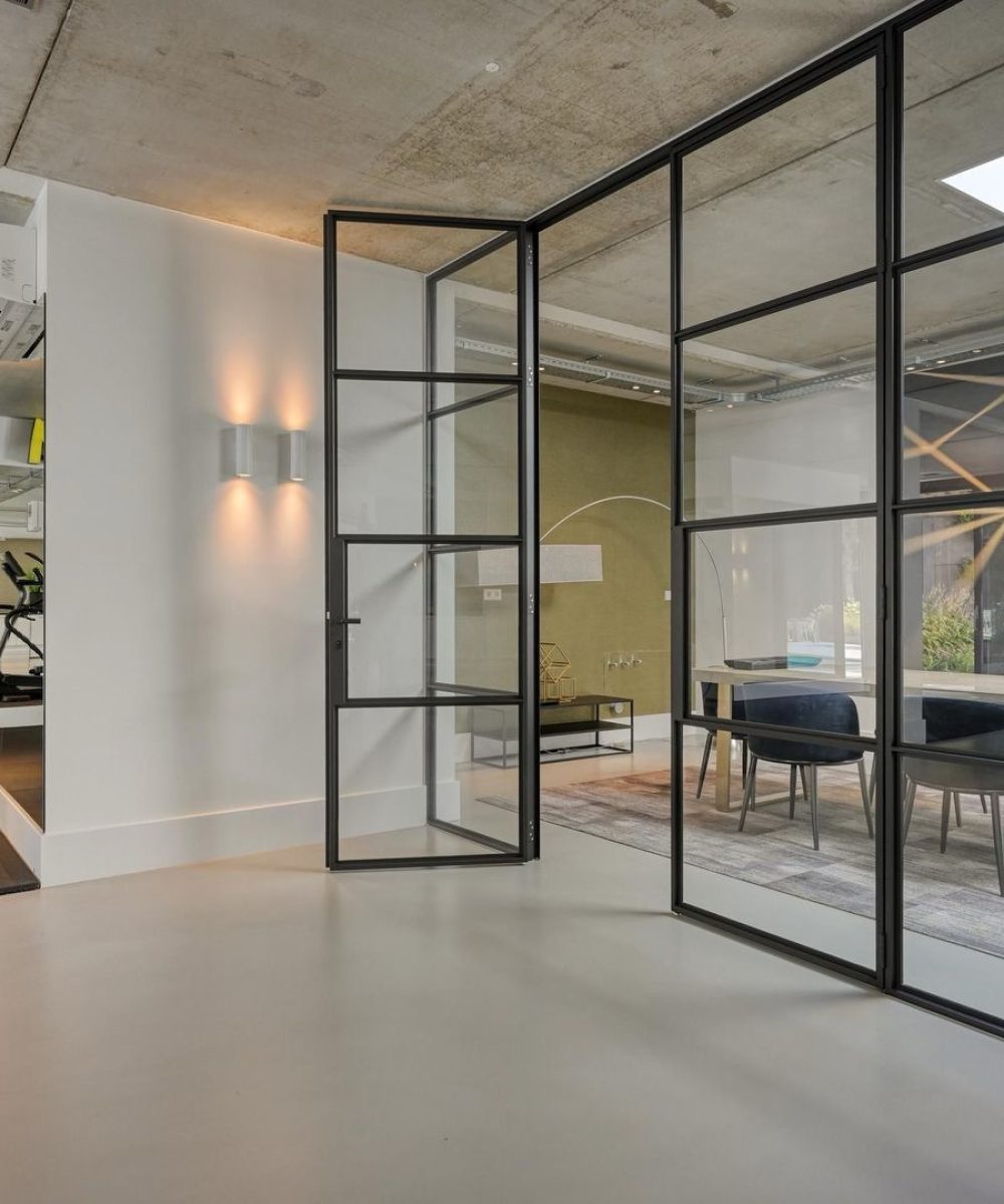 Fitnessruimte achter een stalen glaswand in Villa Zuidduinen in Noordwijk. Ontwerp KamerlingvanderBurgh.