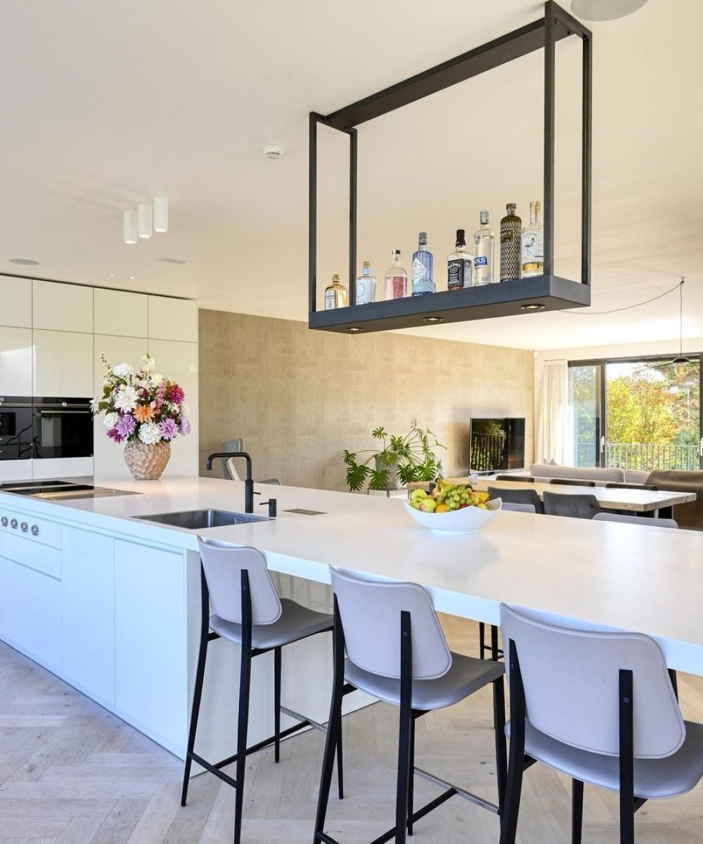 Keuken met kookeiland en zwarte hanglamp in Villa Zuidduinen in Noordwijk. Ontwerp KamerlingvanderBurgh.